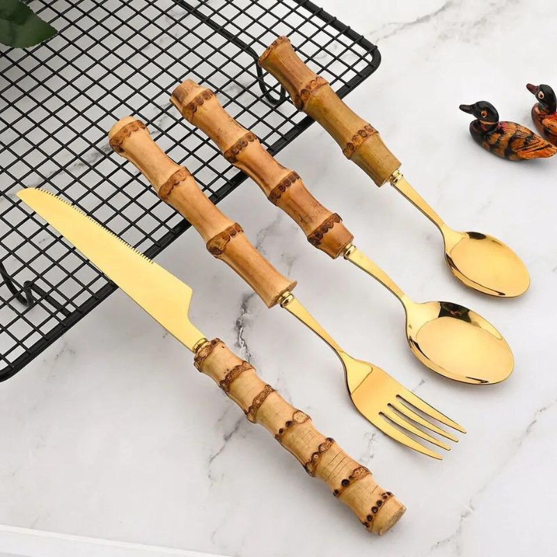 gold bamboo-handled cutlery set arranged on marble surface