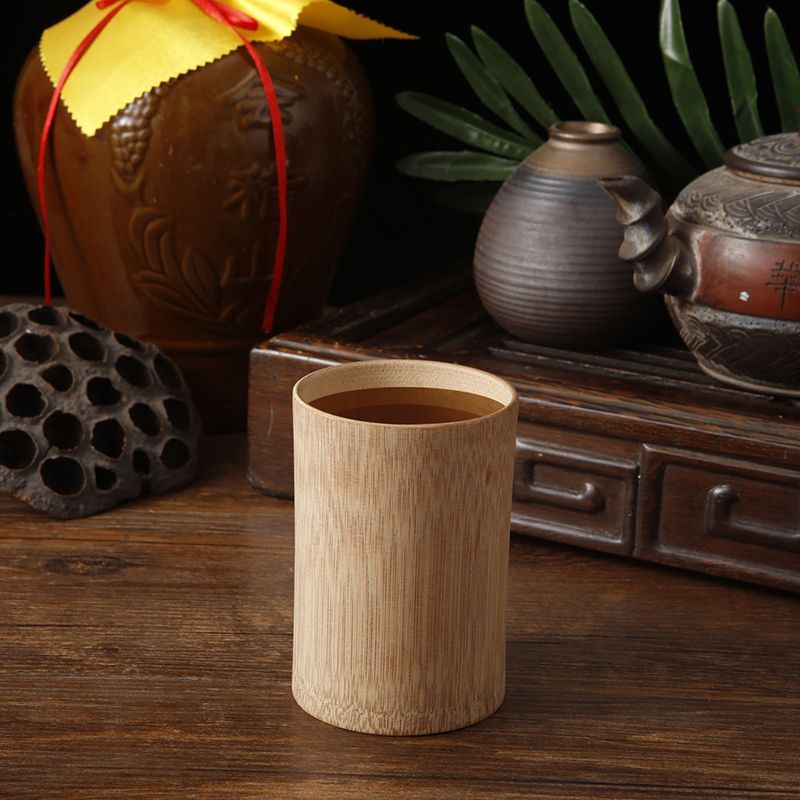 tall bamboo cup beside teapot and decorative items