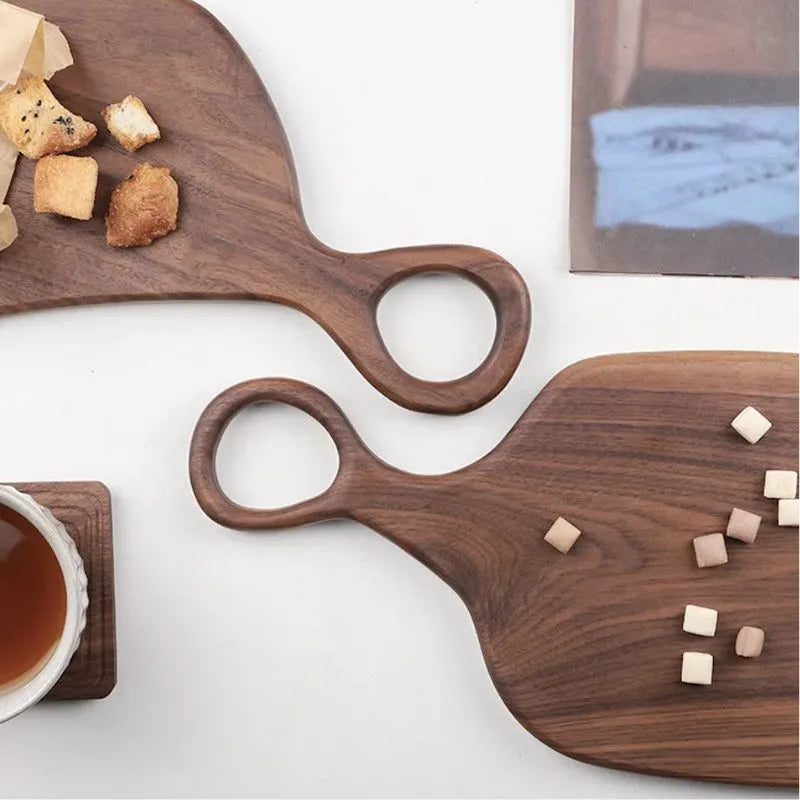 Two wooden serving boards with handles on a white surface, one with croutons and the other with small cubes.